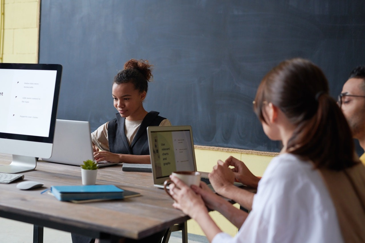 Concentrated students seated at table with laptops.