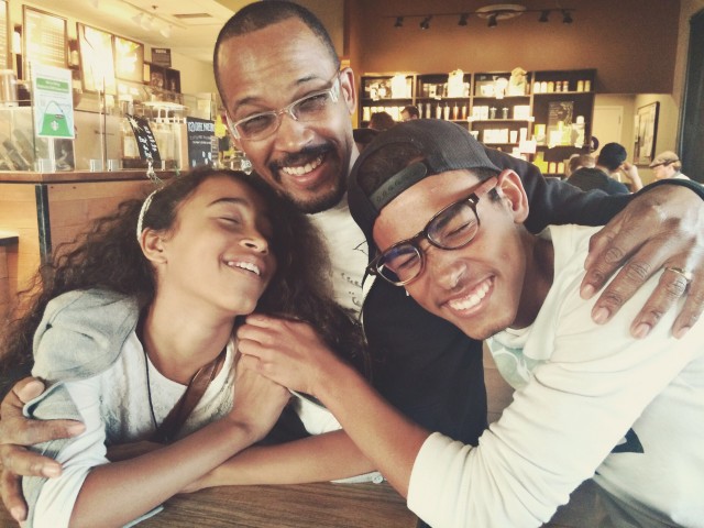 Teenage son and daughter hugging father in a coffee shop.