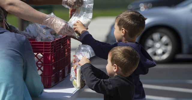 Two young boys holding bagged lunches representing food insecurity.